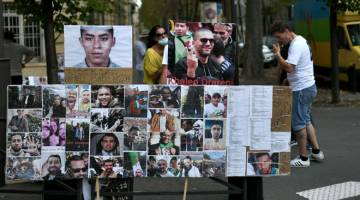 TANDA SOKONGAN: Penunjuk perasaan berkumpul di sebelah potret tahanan Algeria di luar kedutaan Algeria di Paris, Perancis kelmarin semasa demonstrasi sebagai tanda sokongan untuk wartawan Algeria Khaled Drareni. — Gambar AFP