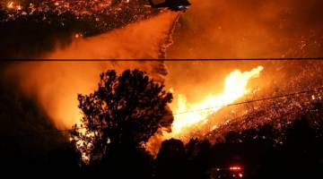 MARAK: Helikopter bomba mencurah air untuk memadam kebakaran hutan di Lake Hughes, California kelmarin. — Gambar AFP