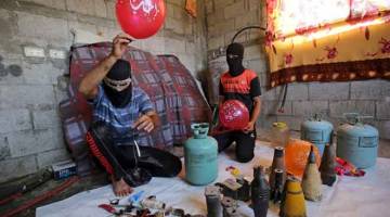 BERBAHAYA: Dua pejuang Palestin menyediakan bahan bakar yang diisi di dalam belon sebagai senjata untuk menentang Israel di Selatan Gaza. — Gambar AFP