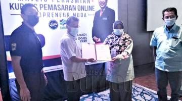 USAHAWAN: Che Abdullah (dua kiri) menyampaikan sijil penyertaan kepada salah seorang peserta yang menyertai kursus pemasaran itu.