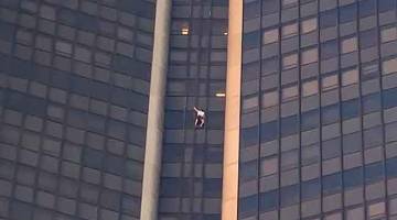 BERANI: Seorang lelaki kelihatan memanjat bangunan Tour Montparnasse, di Paris sebelum ditangkap. — Gambar AFP