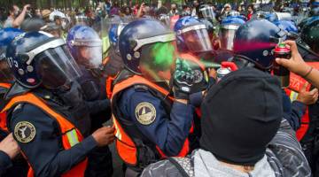 GANAS: Para penunjuk perasaan menyembur cat ke arah polis antirusuhan di Kota Mexico, kelmarin semasa perarakan ulang tahun keenam kehilangan 43 pelajar Kolej Latihan Perguruan Ayotzinapa. — Gambar AFP