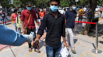 PATUH: Para pelajar diperiksa suhu badan ketika tiba untuk menduduki ujian lanjut untuk kemasukan ke kolej kejuruteraan utama negara di sebuah pusat peperiksaan di Noida, kelmarin. — Gambar AFP