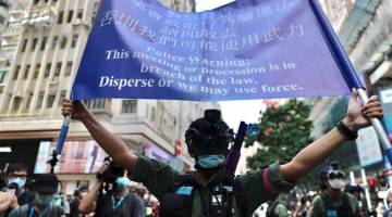 AMARAN: Anggota polis memegang sepanduk yang mengarahkan penunjuk perasaan bersurai semasa sambutan Hari Kebangsaan China di Hong Kong semalam. — Gambar AFP