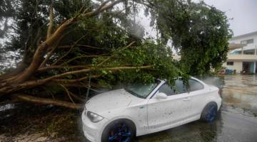 TUMBANG: Gambar menunjukkan sebuah kereta ditimpa pokok yang tumbang ketika Taufan Delta membadai bandar Cancun          di negeri Quintana Roo, Mexico kelmarin. — Gambar AFP