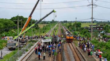 TRAGEDI: Bangkai bas yang dilanggar kereta api diangkat dengan kren dari atas landasan berhampiran stesen kereta api Khlong Kwaeng Klan di wilayah Chachoengsao, timur Bangkok semalam. — Gambar AFP