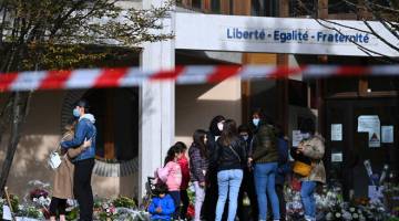 SEDIH: Orang ramai kelihatan berkumpul untuk memberi penghormatan kepada Samuel Paty di hadapan sekolah Bois d’Aulne             di Conflans-Sainte-Honorine, barat laut Paris kelmarin. — Gambar AFP