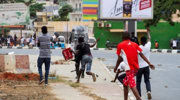 TIDAK TERKAWAL: Penunjuk perasaan melontar batu ke pegawai polis yang cuba meleraikan demonstrasi di Luanda. — Gambar AFP
