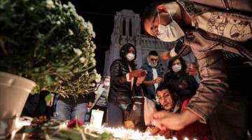 SUASANA SURAM: Orang ramai menyalakan lilin di luar Basilika Notre-Dame di Nice, Perancis                     kelmarin sebagai tanda penghormatan buat tiga mangsa yang terbunuh dalam serangan pisau di gereja tersebut. — Gambar AFP 