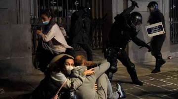 HURU-HARA: Anggota polis menggunakan belantan untuk meleraikan penunjuk perasaan              yang menyertai protes terhadap sekatan COVID-19 di Barcelona, Sepanyol kelmarin. — Gambar AFP