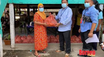 BANTUAN: Iskandar (tengah) menyerahkan bantuan bakul makanan kepada warganya.