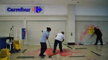 KECOH: Para pekerja membersihkan cat merah yang dihamburkan di hadapan pintu masuk pasar raya Carrefour oleh penunjuk perasaan yang memprotes kematian Silveira Freitas di Rio de Janeiro, kelmarin. — Gambar AFP