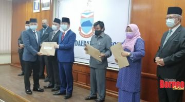 SERAH: Isnin menyerahkan surat watikah pelantikan kepada salah seorang ketua adat yang hadir pada majlis yang diadakan itu.