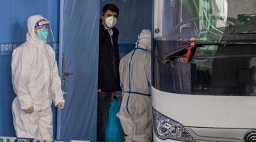 TUGASAN PENTING: Salah seorang pakar WHO yang ditugaskan untuk menyiasat asal usul COVID-19 dilihat menaiki bas selepas tiba bersama pasukannya di kawasan ketibaan antarabangsa           di lapangan terbang Wuhan semalam. — Gambar AFP