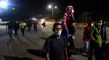 KARAVAN BAHARU: Pendatang Honduras dilihat berjalan kaki dari Great Metropolitan Central           di San Pedro Sula, 180 kilometer utara Tegucigalpa kelmarin ketika mereka dalam perjalanan untuk berhijrah ke Amerika Syarikat. — Gambar AFP