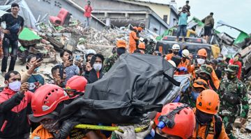 USAHA MENCARI: Para penyelamat membawa mayat mangsa runtuhan bangunan di Mamuju kelmarin, sehari selepas gempa bumi dengan skala 6.2-magnitude di Pulau Sulawesi Indonesia. — Gambar AFP