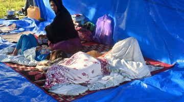 HILANG TEMPAT BERTEDUH: Sebuah keluarga sedang berehat di khemah, kelmarin berikutan gempa bumi berskala 6.2 magnitud di Mamuju pada Jumaat lepas. — Gambar AFP