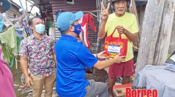 GEMBIRA: Seorang warga emas di Kg. Tanjung Aru menerima beg cenderahati Tahun Baharu Cina daripada Mohd. Reduan.