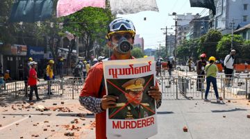 PROTES: Penunjuk perasaan memegang poster memaparkan gambar ketua angkatan tentera Myanmar Min Aung Hlaing         semasa demonstrasi terhadap rampasan kuasa tentera di Yangon pada Selasa lepas. — Gambar AFP