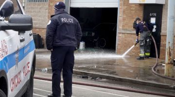BERDARAH: Anggota bomba membersihkan darah yang mengotori kawasan kaki lima premis susulan kes tembakan di garaj tersebut di Chicago, Illinois kelmarin. — Gambar AFP