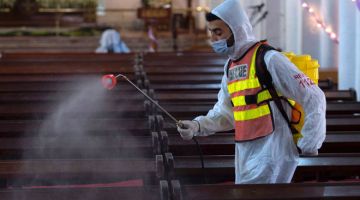 KEKANG PENULARAN: Seorang pekerja kesihatan melakukan kerja sanitasi di sebuah gereja di Peshawar. — Gambar AFP