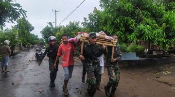 DITEMUI: Anggota keselamatan mengusung mayat mangsa yang ditemui selepas banjir kilat                  di pulau Lembata, Timor Timur kelmarin. — Gambar AFP