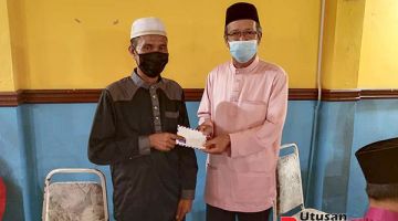 SUMBANGAN: Kamarlin (kanan) menyampaikan sumbangan sempena bulan Ramadhan kepada salah seorang penerima dalam majlis berbuka puasa yang diadakan dekat Sipitang.