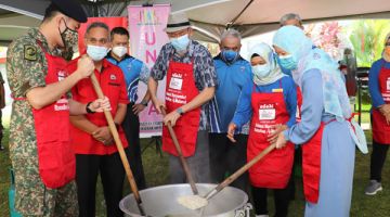 BUBUR LAMBUK: Tun Juhar (tengah) dan Toh Puan Norlidah (kanan) ketika mengacau bubur lambuk.