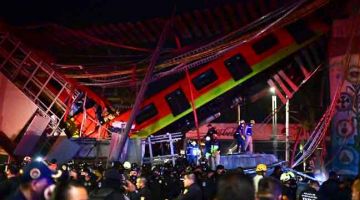 RUNTUH: Anggota bomba dan penyelamat menjalankan misi untuk menyelamatkan mangsa yang terperangkap selepas landasan kereta api runtuh di selatan Kota Mexico kelmarin. — Gambar AFP