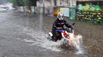 BANJIR: Seorang lelaki menunggang motosikalnya melalui kawasan yang dilanda banjir akibat hujan lebat selepas Siklon Tauktae membadai Mumbai di India kelmarin. — Gambar AFP