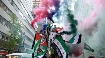 TANDA SOLIDARITI: Penunjuk perasaan memegang bendera Palestin dan Syria ketika perhimpunan sebagai lambang solidariti dengan Palestin di tengah Manhattan, New York kelmarin. — Gambar AFP