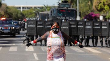 BERANI: Wanita orang asli berdiri di hadapan pasukan polis   ketika menyertai protes di Brasilia, kelmarin. — Gambar AFP
