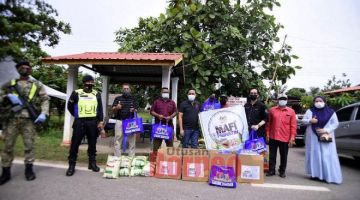 SERAH: Japlin (lima kanan) menyerahkan sumbangan kepada petugas barisan hadapan yang bertugas di pos kawalan pintu masuk utama ke kampung yang dikenakan PKPD.