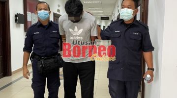 Tertuduh (tengah) diiring polis semasa berada di Kompleks Mahkamah Kuching.