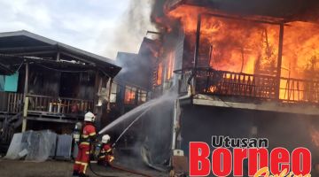 OPERASI: Anggota bomba menjalankan kerja pemadaman supaya api tidak merebak ke rumah berhampiran.