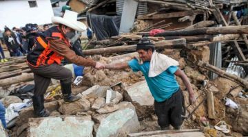 Castillo (kiri) menghulurkan tangan kepada seorang lelaki yang berdiri di tengah-tengah serpihan rumahnya yang musnah dalam kejadian gempa bumi di wilayah Amazon Peru pada Ahad lepas. - Gambar AFP