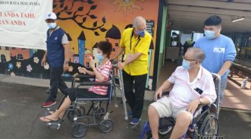 BANTU: Sebastian (berbaju kuning) menyorong kerusi roda Sim, sambil berbual dengan Tan, yang dibantu oleh cucunya, selepas menunaikan kewajipan mereka mengundi di SK Jalan Bintang. 