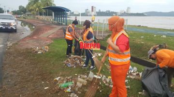KERJA: Anggota pembersihan DBKK membersihkan sampah di kawasan Taman Awam Teluk Likas.