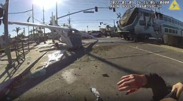 Tangkap layar gambar kamera badan dikeluarkan Jabatan Polis Los Angeles kelmarin menunjukkan kereta api bergerak laju ke arah pesawat yang terhempas ketika anggota polis menarik juruterbang (bawah kanan) dari landasan kereta api di California. — Gambar AFP