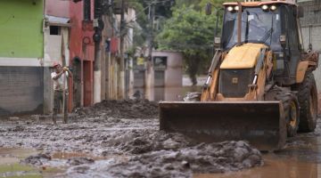 Penduduk membersihkan jalan raya selepas banjir akibat hujan lebat di wilayah Minas Gerais, Brazil kelmarin. — Gambar AFP