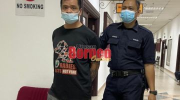 Tertuduh (kiri) diiring polis semasa berada di lobi Mahkamah Kuching.