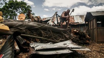 Jocelyn Germain, 56, menggunakan kapak untuk memotong pokok yang menimpa rumah anak lelakinya selepas Siklon Batsirai melanda di Irondro, pada Selasa lepas. — Gambar AFP