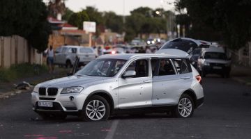 GAGAL: Sebuah kereta dipenuhi lubang peluru kelihatan di tengah-tengah jalan raya selepas cubaan merompak wang tunai yang gagal di pinggir bandar Rosettenville, Johannesburg kelmarin. — Gambar AFP 