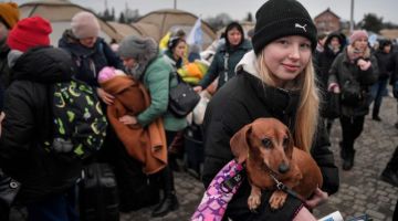 Seorang kanak-kanak mengendong haiwan kesayangannya selepas merentasi sempadan Ukraine untuk memasuki Poland di lintasan sempadan di Medyka, tenggara Poland kelmarin. - Gambar AFP