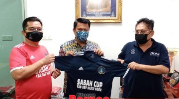 SERAHKAN: Azman menyerahkan baju rasmi kejohanan kepada Kassim (tengah) selepas pelantikan itu sambil diperhatikan Setiausaha Eksekutif SAFA, David Wisom.