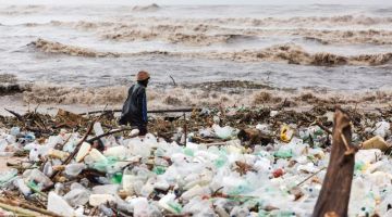 Seorang lelaki kelihatan menyelongkar serpihan di pantai Blue Lagoon selepas hujan lebat dan ribut mencetuskan banjir lumpur di Durban, Afrika Selatan kelmarin. — Gambar AFP