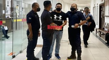 Tertuduh (tengah) diiring polis semasa berada di Kompleks Mahkamah Kuching. 