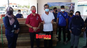 PRIHATIN: Reduan (dua kiri) merakamkan gambar kenangan bersama seorang penerima bantuan.