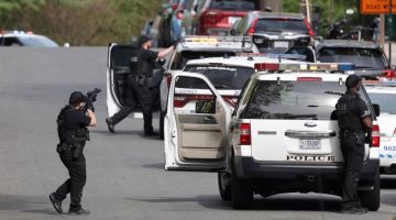 Polis Metropolitan mengacukan senjata mereka ke arah sebuah bangunan apartmen di Van Ness Street Northwest dalam kejadian tembakan di Washington, kelmarin. — Gambar AFP