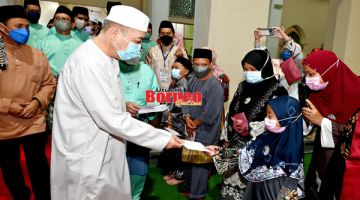 SUMBANGAN: Hajiji menyampaikan sumbangan kepada anak-anak istimewa, OKU dan asnaf pada majlis itu.